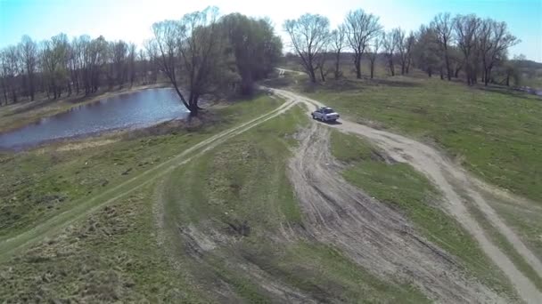 Samochód jedzie w pole na polnej drodze. Widok z lotu ptaka — Wideo stockowe