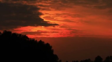 Bulutlarda kırmızı günbatımı gökyüzü ve ahşap. Zaman atlamalı