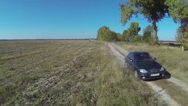 Samotny zielony samochód na wiejskiej drodze brudu. Antenowe letni dzień — Wideo stockowe