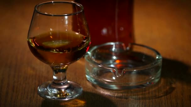 Ijs valt in een glas met cognac, whisky — Stockvideo