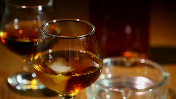 Ijs valt in een glas met cognac, whisky close-up — Stockvideo