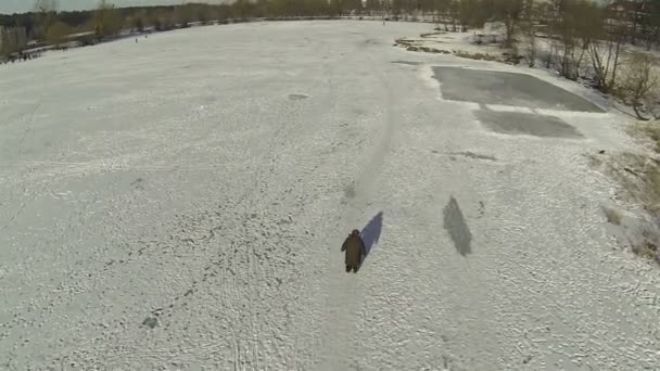 Siluett av gående person på frusen sjö. Antenn — Stockvideo