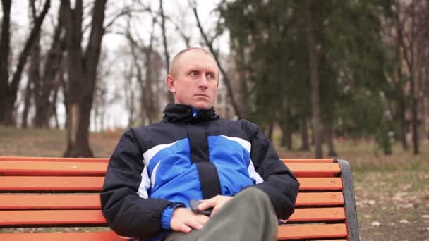 Hombre malo adulto hablando en el móvil en el parque. Vista frontal — Vídeos de Stock