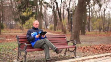 Parkta bir tablet üzerinde çalışan yetişkin adam