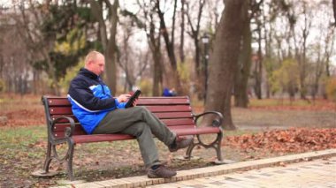 Parkta bir tablet üzerinde çalışan yetişkin adam