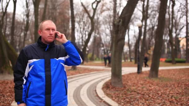 Hombre adulto hablando en el móvil en el parque de otoño — Vídeo de stock