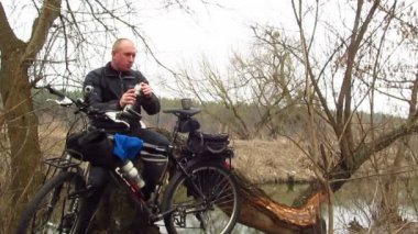 Yetişkin adam bisikletçi açık havada Nehri yakınında yiyor