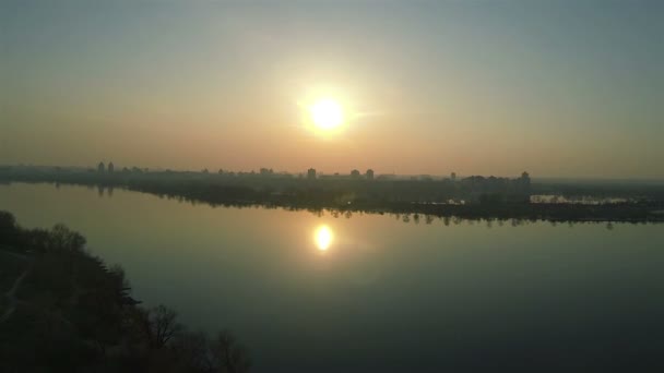 Gyönyörű naplemente a nagy folyó és a város. Légi felvétel, hátsó repülni — Stock videók