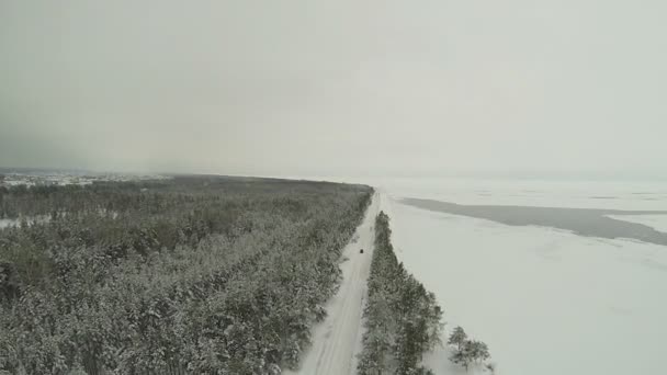 Voiture solitaire sur route enneigée et en bois. Plan lent aérien — Video