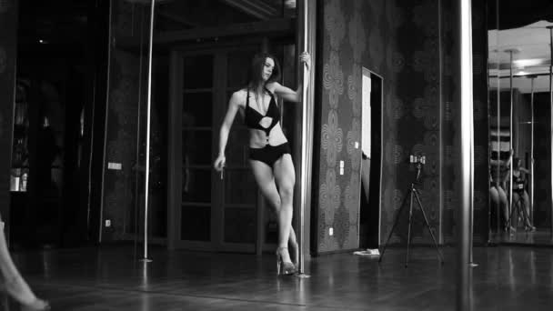 Молода сексуальна дівчина стриптизерка поул-танцівниця в поул-холі. Чорно-білий — стокове відео