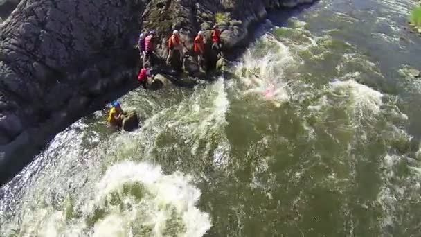 La gente con chalecos salvavidas salta al río de montaña. Parte superior aérea — Vídeo de stock