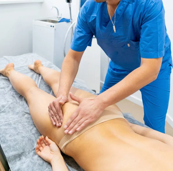 Treatment procedures. The patient on the massage table. Anticellulite massage. The masseur massages the female buttocks. Ass massage. — Zdjęcie stockowe