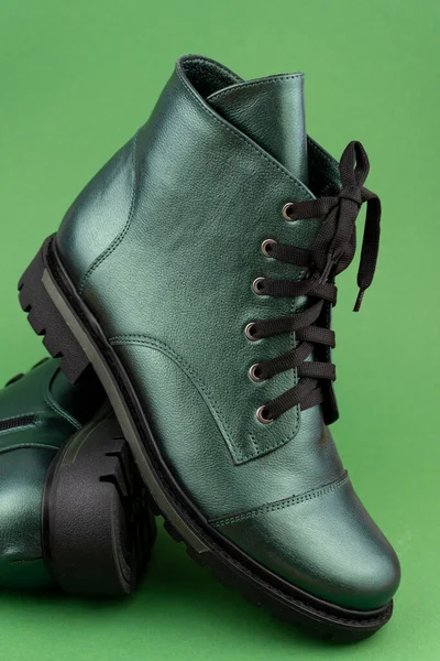 Green leather shoes. Winter and autumn off-season boots. Stylish boot isolated on background. Close-up. Laces, tractor sole, comfortable last. Casual style. Copy space. Pearlescent fashionable color.