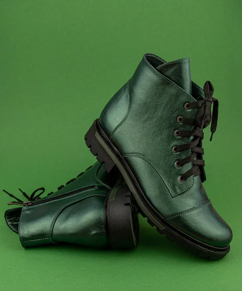 Green leather shoes. Winter and autumn off-season boots. Stylish boot isolated on background. Close-up. Laces, tractor sole, comfortable last. Casual style. Copy space. Pearlescent fashionable color.