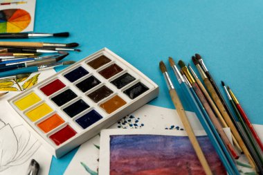 Suluboya boya ve fırça. Sanatçının çalışma yeri ve masası. Renk paleti. Arkaplan çizimi. Metnin için yer.