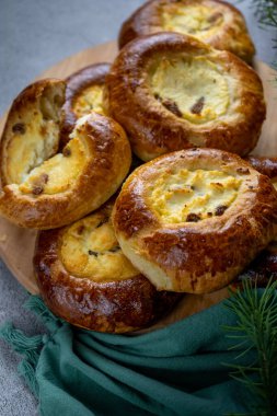 Peynirli kekler. Fırında mayalı açık turtalar ev yapımı kekler. Masada yemek var. Porsiyonlu turtalar. Dolgu için süzme peynir ve kuru üzüm. Peynirli kek.