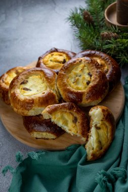 Peynirli kekler. Fırında mayalı açık turtalar ev yapımı kekler. Masada yemek var. Porsiyonlu turtalar. Dolgu için süzme peynir ve kuru üzüm. Peynirli kek.