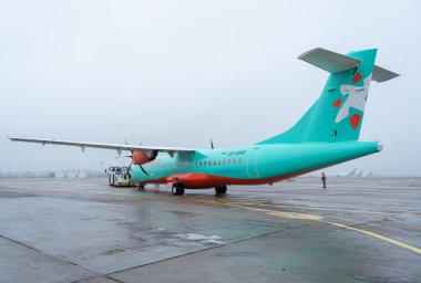 Ukrayna, Kyiv - 29 Aralık 2020: Yolcu uçağı kalkış için kalkış için çekilmiştir. Sisli havaalanı, görüş mesafesi ve hava durumu kötü. Uçak ATR 72-60 UR-RWD Windrose Havayolları. Helikal, bıçaklar.