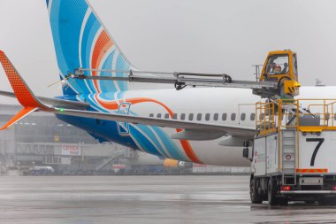 Ukrayna, Kyiv - 29 Aralık 2020: havaalanında Deice. Flydubai yolcu uçakları kalkıştan önce antifriz ile tedavi edilir. Kışın havaalanı. Uçuş servisi. Meyve suyu makinesi. Siste uçak..