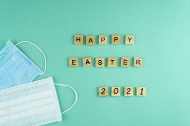 Mutlu Paskalyalar 2021 Tıbbi maskeler. Sözcük ahşap harflerle yazılmıştır. Yukarıdan bak. Motivasyon. Tıbbi maskeler. Maske. Uzayı kopyala Doktorlar için kartpostal.