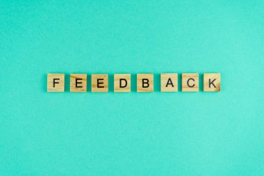 Kelime geribildirimi. Sözcük ahşap harflerle yazılmıştır. Üst Manzara. Motivasyon. Mavi arka plan. Boşluğu kopyala.