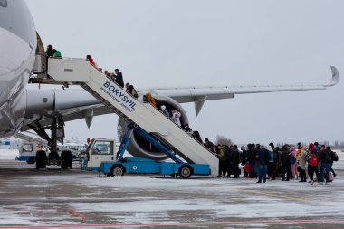 Ukrayna, Kyiv - 12 Şubat 2021: Katar Havayolları A7-ALW Havalimanı A350-900 sefer sayılı yolcu uçağı. Kış havaalanında. Yolcular için bir merdiven. Pistte kar var. İnsanlar seyahat eder