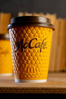 Ukrayna, Kyiv - 17 Şubat 2021: McDonalds 'dan sarı bardak kahve. Kağıt bardak McCafe. Masada gölgeli bir fincan var. Fast food restoranında menü.