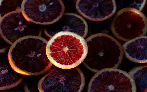 Red oranges fruit background. Sliced juicy orange. Food. Summer concept. Close-up on the light.