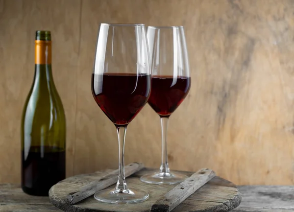 Two glasses of red wine. The bottle of wine is on the table. Wine background. Still life. Alcoholic drink in a glass. Wooden background.