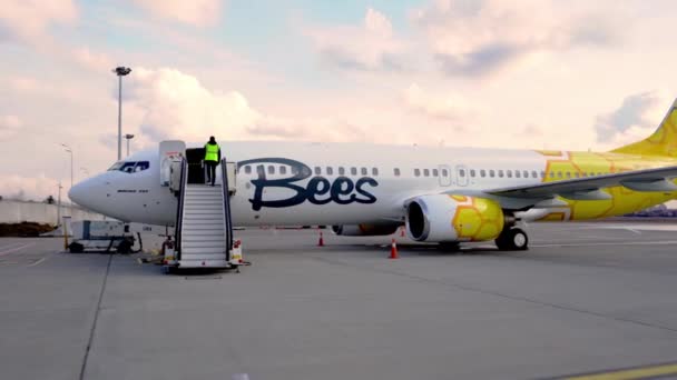 Ukraine, Kiew - 19. März 2021: Flugzeug der Bees Airline auf dem Vorfeld. Passagiere einsteigen. Leiter auf der Plattform. Boeing 737-800 UR-UBA Passagierflugzeug — Stockvideo