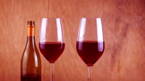 Zwei Gläser Rotwein. Alkoholisches Getränk im Glas. Eine Flasche Wein. Hölzerner Hintergrund. — Stockvideo