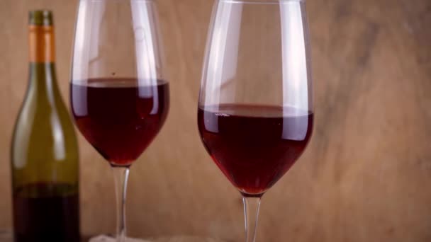 两杯红葡萄酒。喝一杯含酒精的饮料.一瓶酒。木制背景. — 图库视频影像