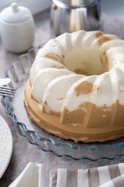 Puding. Süzme peynirli, çikolatalı tatlı. Jöle. Masada beyaz kek var. Tatlı puding yuvarlaktır ve ortasında bir delik vardır. Masada hala hayat var. Kahvaltı..