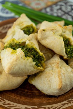 Yabani sarımsaklı turtalar ve yeşil soğanlı. Ev yapımı yemek. Puf böreği. Tabakta pişiriyorum, yakın plan. Yerel yemek. Ramson.