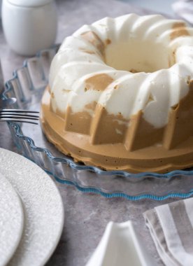Puding. Süzme peynirli, çikolatalı tatlı. Jöle. Masada beyaz kek var. Tatlı puding yuvarlaktır ve ortasında bir delik vardır. Masada hala hayat var. Kahvaltı..
