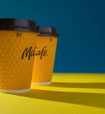 Ukrayna, Kyiv - 17 Şubat 2021: McDonalds 'dan sarı bardak kahve. Kağıt bardak McCafe. Masada gölgeli bir fincan var. Fast food restoranında menü.