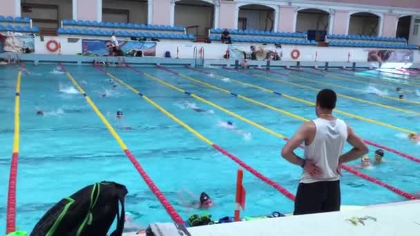 Oekraïne, Kiev - 30 mei 2018: Open openbaar groot zwembad. Veel mensen zwemmen op de paden. Kinderen gaan sporten. Jongens en meisjes zwemmen. Opleiding. Coach — Stockvideo