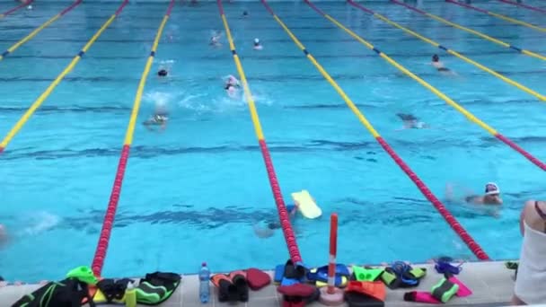 Ukraina, Kiev - 30 maj 2018: Öppen offentlig stor pool. Många simmar på stigar. Barn går in och idrottar. Pojkar och flickor simmar. Träning. Tränare — Stockvideo