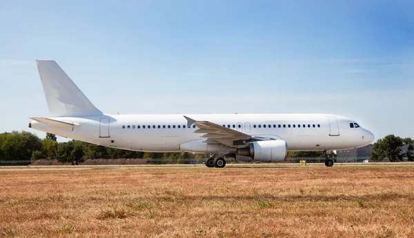 A white plane on the airport runway is taxiing. Takeoff and landing. Arrival and departure. Place for text. Passenger plane mockup. Airplane flight. Travel by air transport. Copy space.