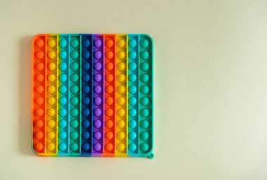 Büyük popit sarı arka planda izole edilmiş. Parlak silikon çizgili oyuncak. Büyük Patlama. Yakın plan. Çocuklar için Popit. Gökkuşağı, parmaklarıyla kabarcıklara bastırıyor. Çocuklar için yeni bir anti-stres oyuncağı. Boşluğu kopyala.