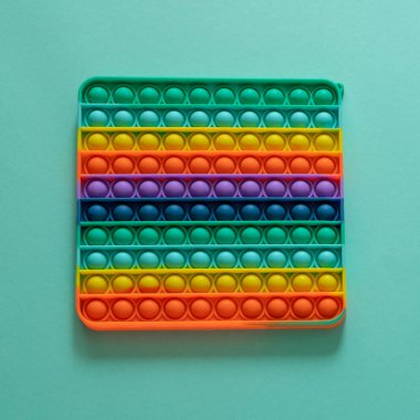 Parlak silikon çizgili oyuncak. Büyük Patlak. Mavi arka planda yakın plan. Gökkuşağıyla oynayan çocuklar için popit, parmaklarıyla kabarcıklara bastırmak, üst manzara. Çocuklar ve yetişkinler için yeni anti-stres oyuncağı.