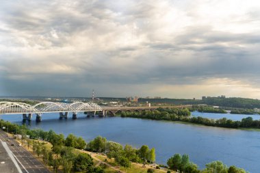 Kyiv 'in sağ yakasının panoramik manzarası. Dinyeper nehri, akşam ve gün batımı. Metro köprüsü. Görüş. Balkondan manzara güzel. Güzel bulutlu gökyüzü. Ukrayna. Kumsalı olan bir baraj..