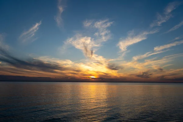 Calm on the coast. The sky in the evening. Water. Sunset sky on the coast. Golden hour. Sky and clouds. Feather cloud. The sun went down below the horizon. Evening sky background. Sunrise landscape.