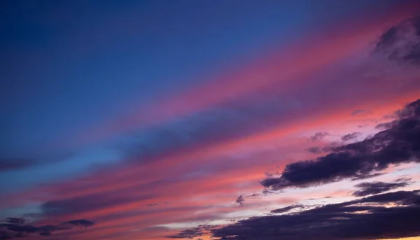 Multi-colored clouds on the dramatic sky. Consumption and sunset clouds. Natural landscape. Pink and blue feather cloud.