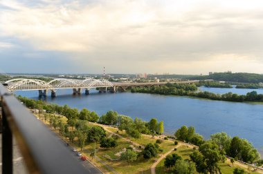 Kyiv 'in sağ yakasının panoramik manzarası. Dinyeper nehri, akşam ve gün batımı. Metro köprüsü. Görüş. Balkondan manzara güzel. Güzel bulutlu gökyüzü. Ukrayna. Kumsalı olan bir baraj..