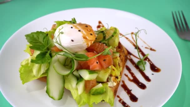 烤鲑鱼和煮鸡蛋 罗勒一个健康的早餐三明治 微绿色 亚麻和芝麻种子 白盘上的乳清食物 面包上有蔬菜的鱼 — 图库视频影像