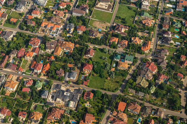 Residential area, rooftops, view from a drone. Cottages in the village. Land view through the airplane window. . Look out the window of a flying plane. Top view of the ground.