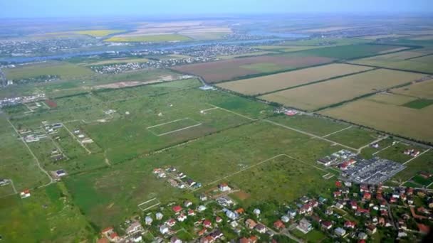 Вид через окно самолета города и крыши. Полет на самолете, пассажир смотрит в окна. Путешествие и посадка. Летит самолет. Жилой район вид сверху. Земля в иллюминаторе — стоковое видео