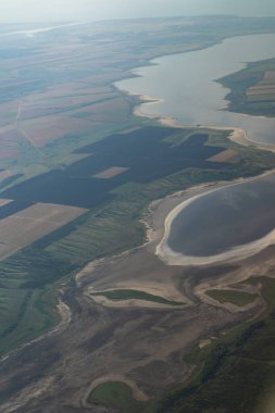 Uçak penceresinden kara manzarası. Tarlalar, yollar, kuş bakışı nehirler. Lomboz. Uçan bir uçağın penceresinden dışarı bak. Zeminin en üst görüntüsü