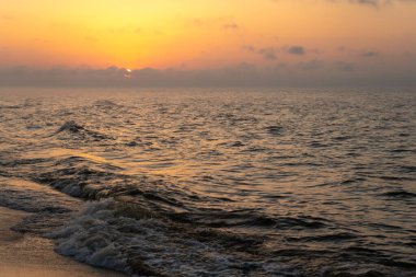 Denizde gün batımı. Akşam güneşi ve patika. Güzel gökyüzü ve bulutlar. Sahildeki manzara. Okyanus kıyısında. Şafak Doğa. Dalgalar ve sörf. Rahatlama ve küme.